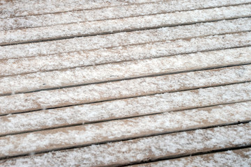 Snowflakes on the wooden deck in southwest Missouri on a winter day. Bokeh effect.
