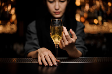 Female bartender serving cocktail with a sugar cube in the glass