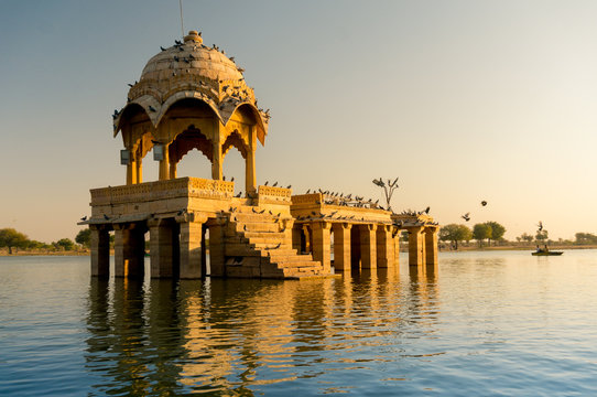 Sandstone chattri domes with steps on gadi sagar lake in jaisalmer at dusk