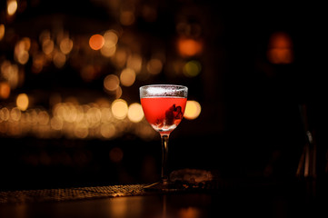 Red cocktail in the ice glass standing on the bar counter