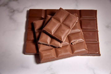 stack of tasty chocolate tablets on a white marble table