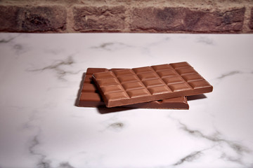 stack of tasty chocolate tablets on a white marble table