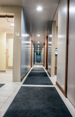 Shiny and clean hallway in mens locker room illuminated with bright LED lights along carpeted floors.