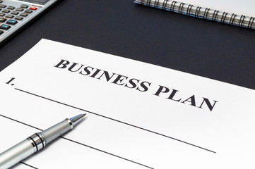 Strategy business plan with pen and notepad on black table.