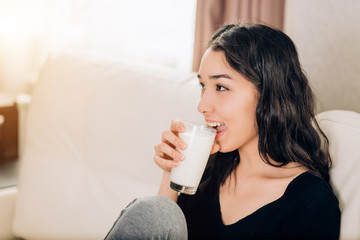 Beautiful young woman with glass of milk at home