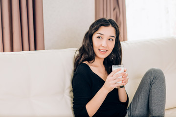 Beautiful young woman with glass of milk at home