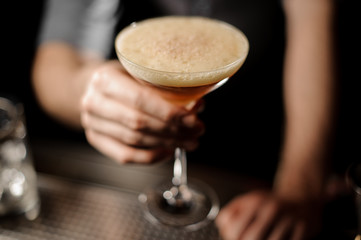 Bartender serving cocktail with a whipped cream and grated nutmeg