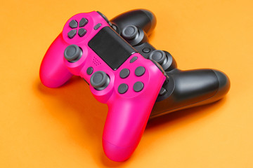 Pink and black gamepad on orange background close up.