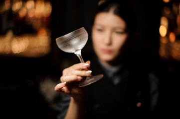 Female bartender looking at the cold matte cocktail glass