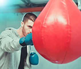 Handsome concentrated male boxer trains hand punches with a punching bag..