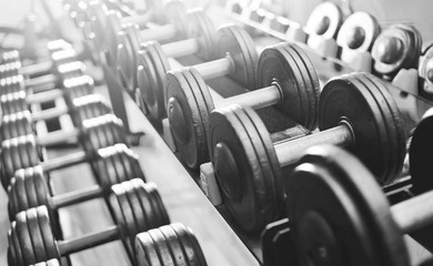 Close up many metal dumbbells on rack in sport fitness center.Highlight. Black and white