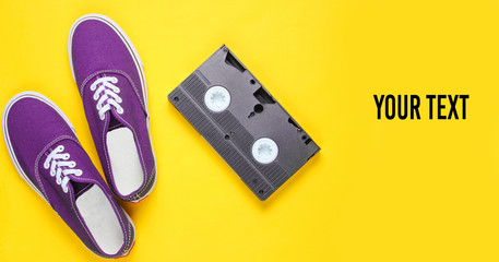 Retro sneakers, video cassette on a yellow background. Pop culture,80s, top view. Copy space