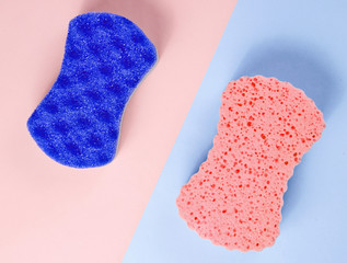Two abrasive double-sided sponges on a pink-blue pastel background. Minimalism, top view