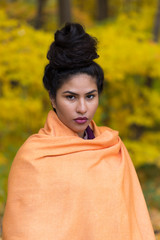 Medium vertical portrait of sultry hispanic young woman with hair up in a high bun draped in an...