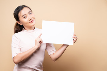 Woman showing paper copy space isolated over beige brown background