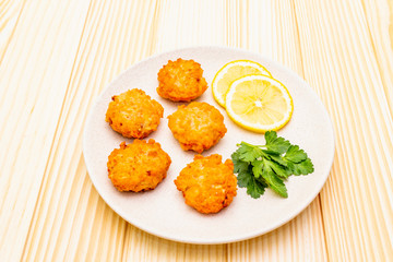 Homemade red fish cakes with lemon and parsley in ceramic plate. On wooden background.