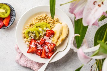 Summer oatmeal with fruit and coconut in a white plate.