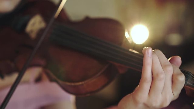 Female violinist playing emotionally melody on the strings with fiddlestick