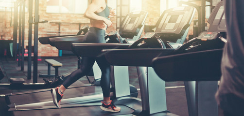 Healthy woman running on a treadmill in a gym. Sport and health concept.