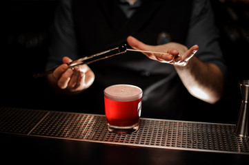 Professional bartender put a one berry on the skewer with tweezers