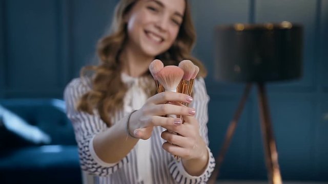 Portrait shot of handsome woman holding brushes in the hands and possing to the camera.