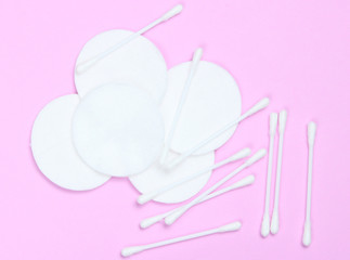 Top view style hygienic cotton swabs and cotton pads on pink background. Minimalism.