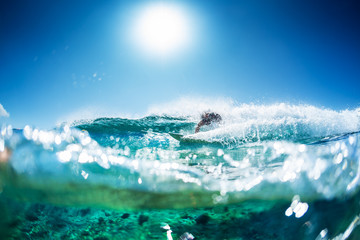Surfer rides the ocean wave with lots of splashes and underwater view of the coral reef