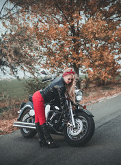 Fototapeta na wymiar Young beautiful caucasian woman posing with motorcycle on the road.