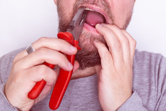 man pulls out a tooth with old metal pliers close-up