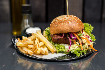 Fried chicken sandwich with vegetables and french fries on a wooden table