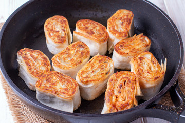 Fried lavash rolls with potatoes and mushrooms in the pan