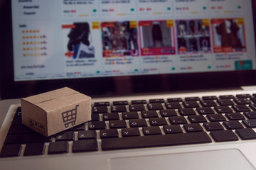 Online shopping : Paper cartons or parcel with a shopping cart logo on a laptop keyboard. Shopping service on The online web and offers home delivery.