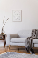 Stylish scandi interior of home space with design grey sofa and retro small table. Living room with design accessories and mock up poster frame. Elegant decor. Brown wooden parquet with modern carpet. © FollowTheFlow