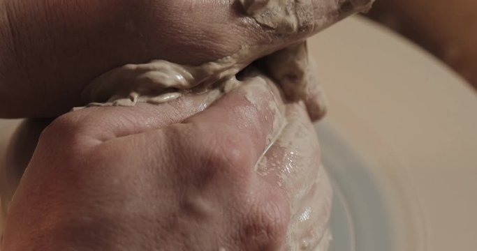 Potter makes pottery from clay close up. Making ceramic products from white clay. Twisted potter's wheel. Man hands making clay jug. Handmade, craft