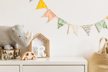 The modern scandinavian newborn baby room with plush rhino, design toys and box on the white shelf....