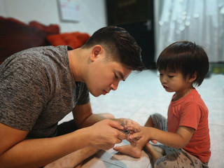 The man is cutting fingernail to his nephew.