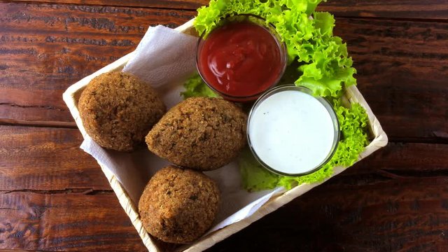 Fried kibbeh with tomato sauce in a basket, over rustic wooden table