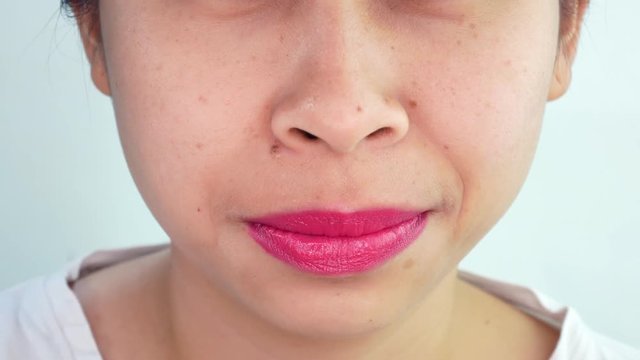 Close up mouth of Asian young woman making sexy face, biting lip with red lips over white background in studio.