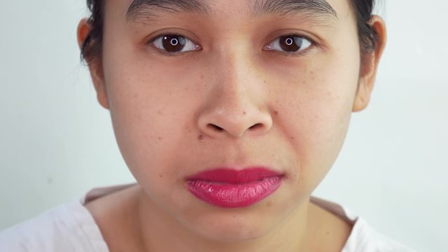 Shot of Asian young woman making face, do not care or unhappy sad face, over white background in studio.
