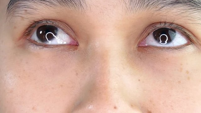 Shot of Asian young woman crying with tear in eye close up on white background.