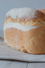 Farmhouse loaf of bread freshly baked on a tea towel with a grey wood background