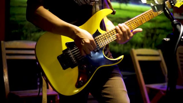 Musicians hands, playing guitar, performing live at night in partying events 