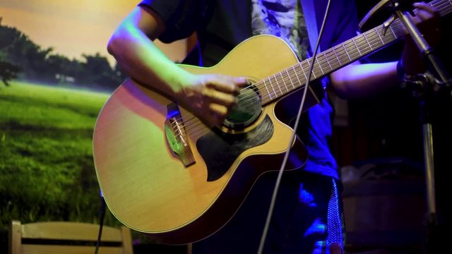Musicians hands, playing guitar, performing live at night in partying events 