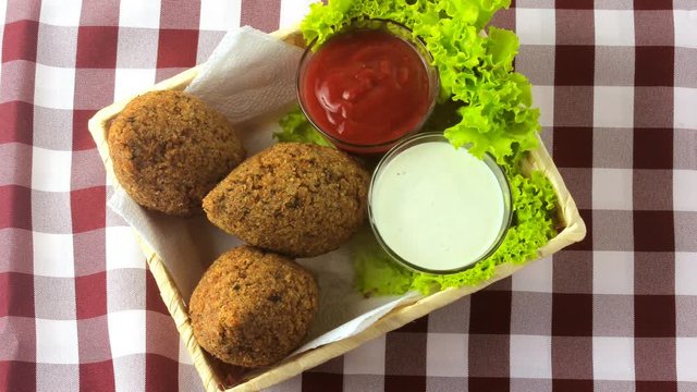 Fried kibbeh with tomato sauce in a basket, over rustic wooden table