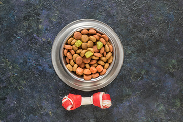 Dog food in metallic bowl on black dark blue background