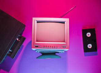 Retro wave, 80s concept. Video player with vhs cassette, old tv, neon light. Top view, flat lay