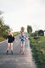 Fototapeta premium Teenage smiling happy girls having fun rollerskating, spending time together