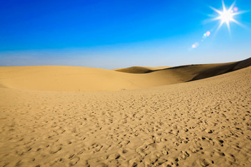 Summer background of sand on beach and blue sky with sun light. Free space for your decoration. 