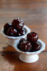 Sweet Jujube or Chinese red date in syrup in white Thai style cup on wood table and space for write wording, Clever idea for fresh fruit preservation, popular sweet, unhealthy food cause of disease