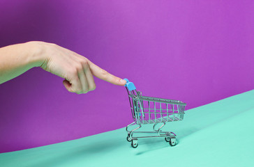 Female finger pushes up sloping empty mini shopping trolley. Shopping concept, delivery